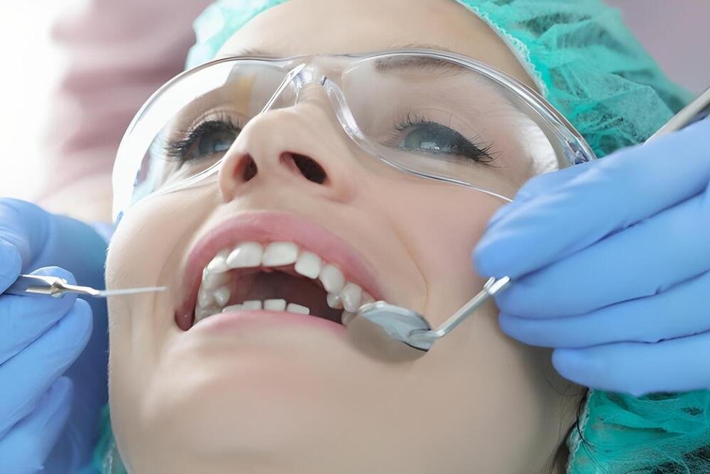 dentist-blog-02 dentista examinar dientes paciente gafas protectoras gorro herramientas dentales