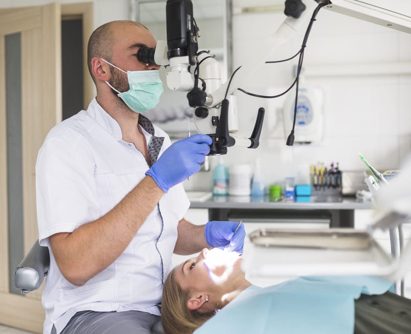 dentista hombre tratando endodoncia paciente mujer